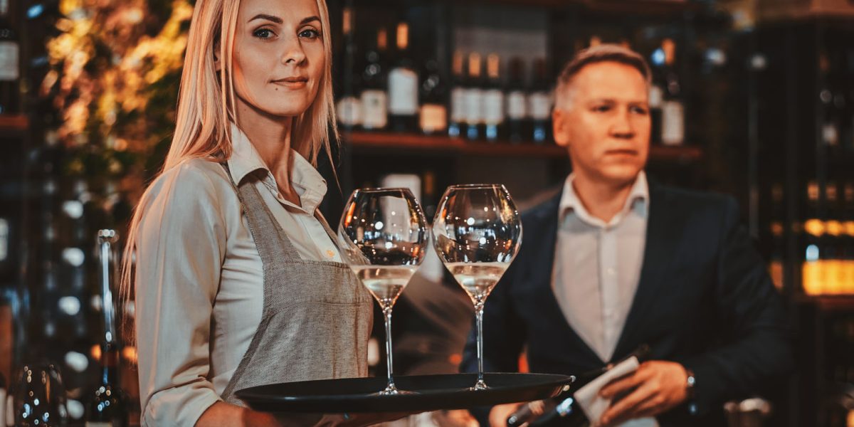 Elegant wine sommelier and his attractive assistant are ready to try new wine at private wine boutique.