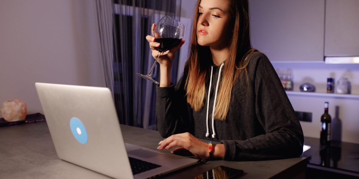 Young,Woman,Sits,And,Works,At,Laptop,And,Drinks,Red